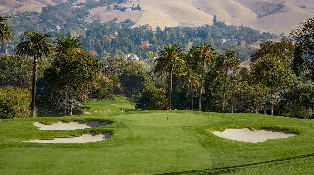 green golf course with hills in the background