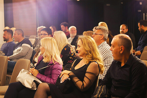 A crowd of people sitting in folding chairs with their attention pointed off camera.
