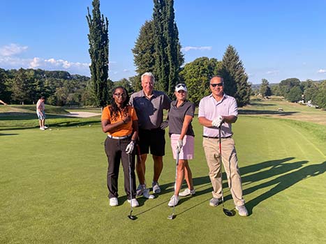 2 men and 2 women in posing with golf clubs on green grass