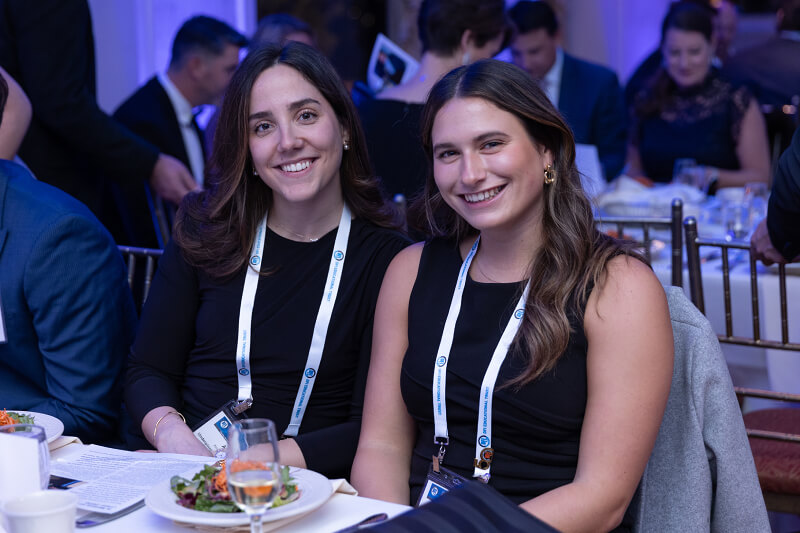 2 women in formal wear sitting at a table.